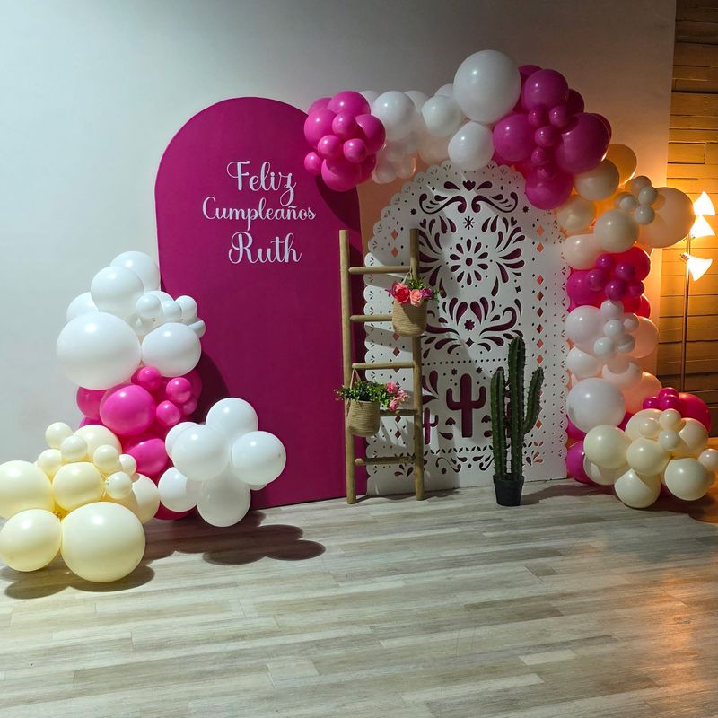 Pink, white and gold balloon arch with a Feliz Cumpleaños backdrop at the Events On Main Co. party venue