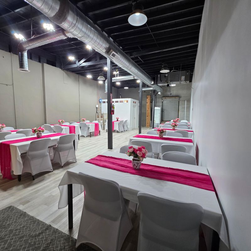 Main hall of Events On Main Co. event center in Magna, Utah, set with tables, white chairs and pink runners