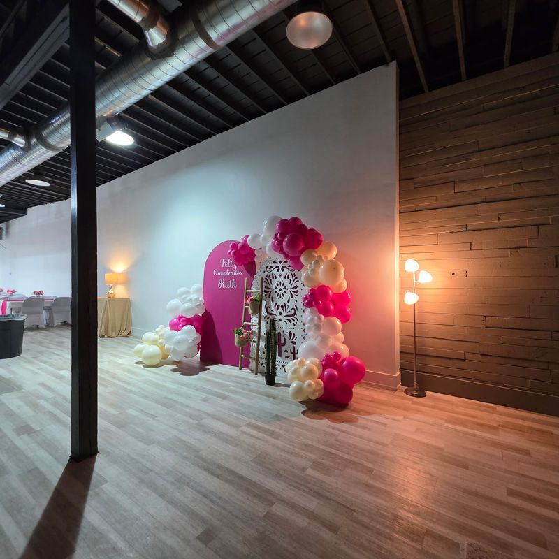 Event rental space in Magna, UT decorated for a birthday party with a pink balloon arch and Feliz Cumpleaños backdrop